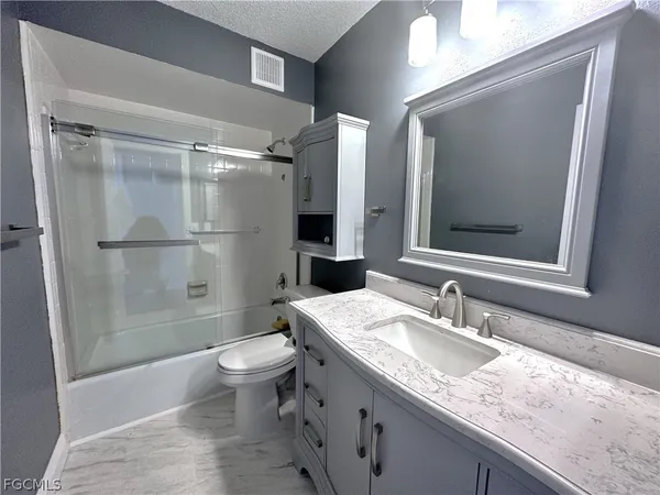 a bathroom with a granite countertop sink toilet and shower