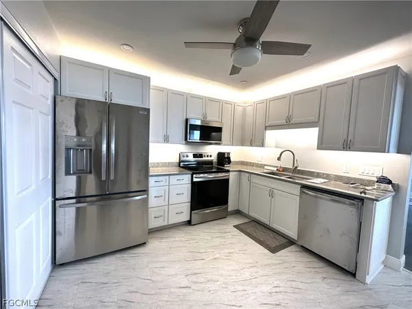 a kitchen with granite countertop a refrigerator stove top oven and sink