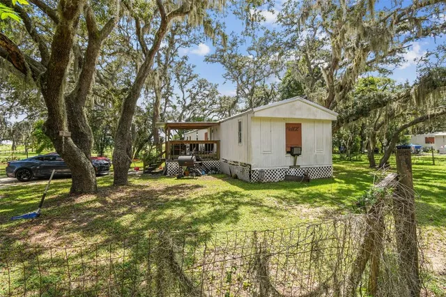 a view of a house with a yard and large trees