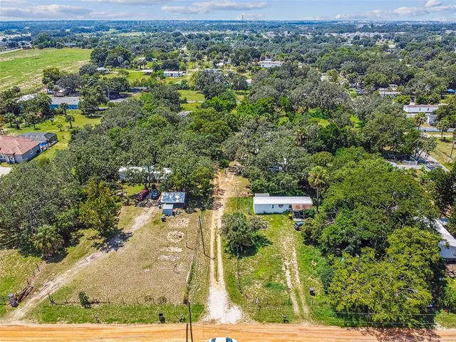 an aerial view of a residential houses with outdoor space and trees