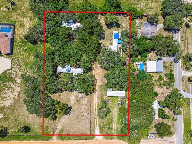 an aerial view of residential houses with outdoor space and trees