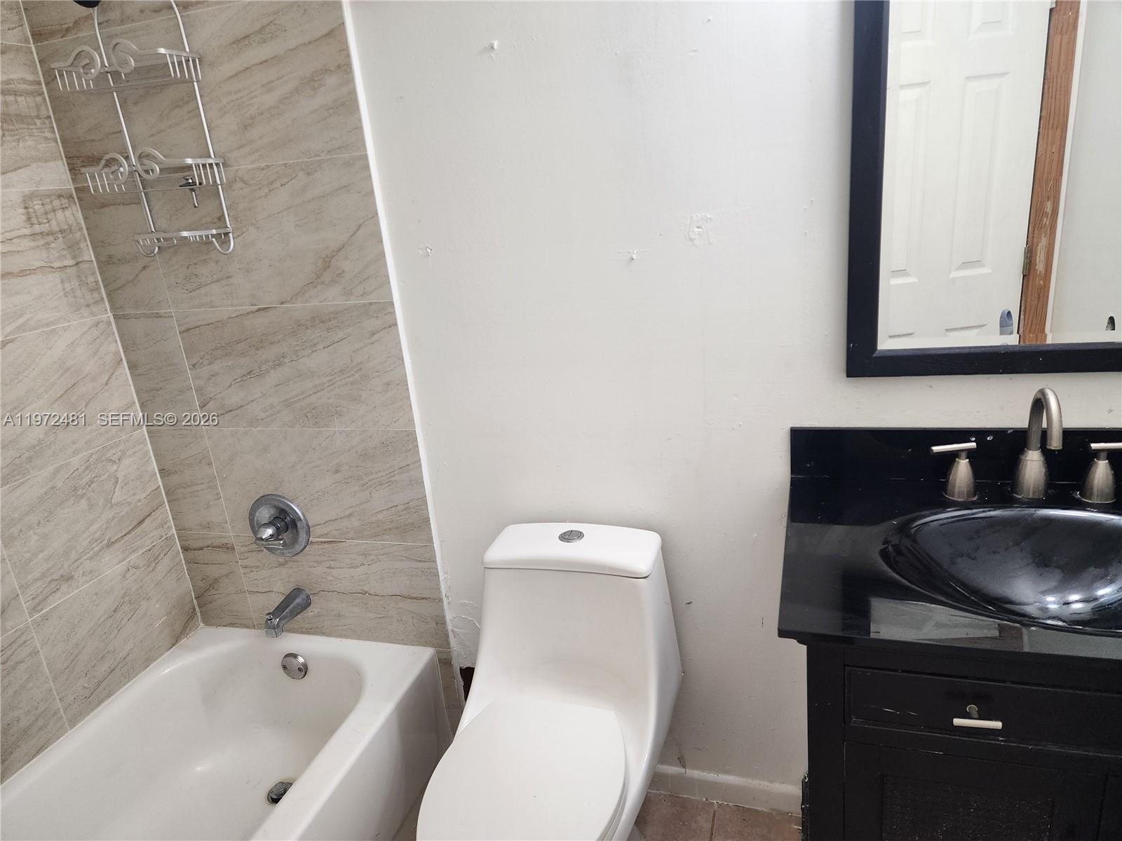 2623 Harding Street Hollywood, FL 33020 - Photo 11 of 12 a bathroom with a granite countertop toilet sink and mirror