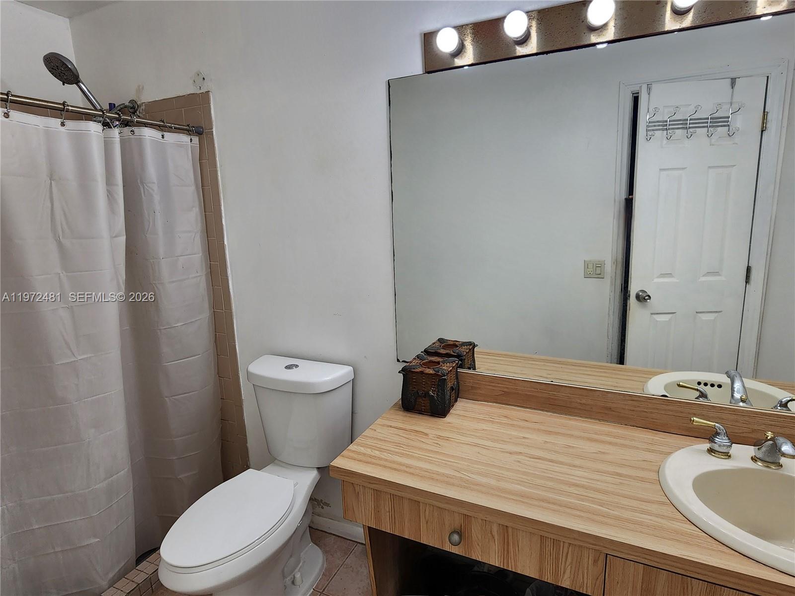 2623 Harding Street Hollywood, FL 33020 - Photo 12 of 12 a bathroom with a sink a toilet and shower curtain