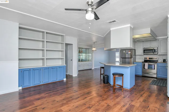 a open kitchen with wooden floors and stainless steel appliances