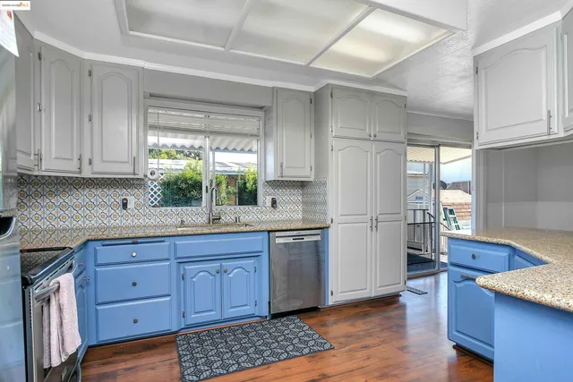 a kitchen with granite countertop appliances a sink cabinets and a window