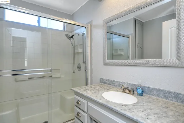 a bathroom with a granite countertop sink a mirror and a shower