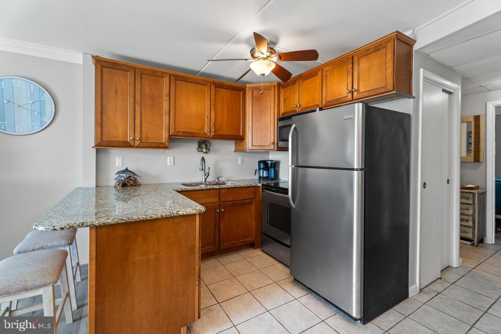 169 Jamestown Road, Unit 20601 Ocean City, MD 21842 - Photo 21 of 35 a kitchen with stainless steel appliances granite countertop a refrigerator a sink and a stove
