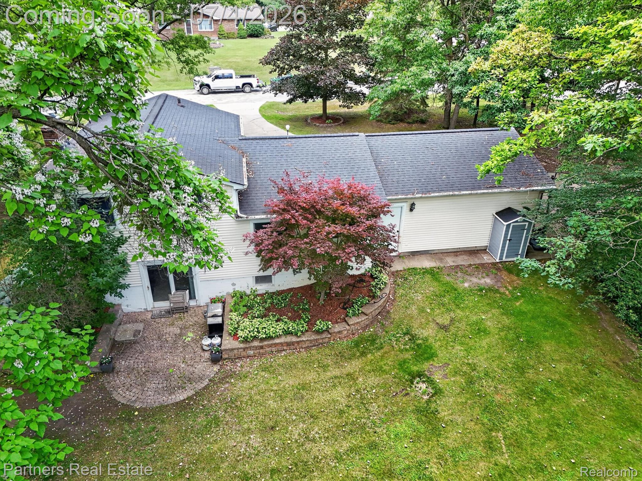 2500 Hubert Road Brighton, MI 48114 - Photo 44 of 53 Rear exterior featuring a paver patio with a stone retaining wall and mature landscaping