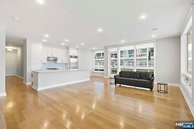a living room with stainless steel appliances furniture and a kitchen view