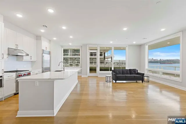 a living room with stainless steel appliances kitchen island granite countertop a large kitchen counter top space and a view of living room