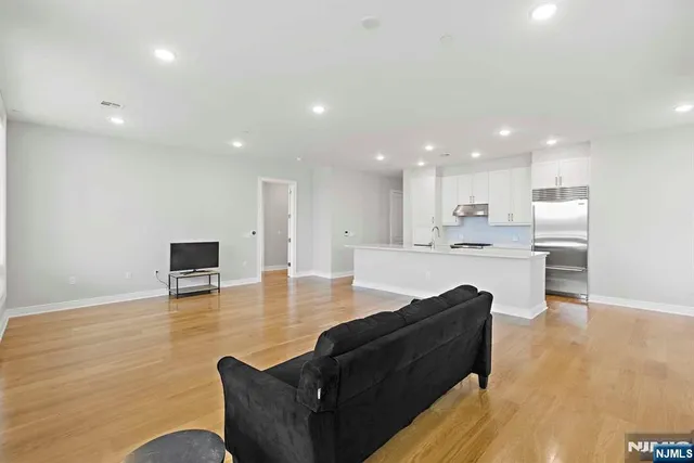 a living room with furniture and kitchen view with wooden floor