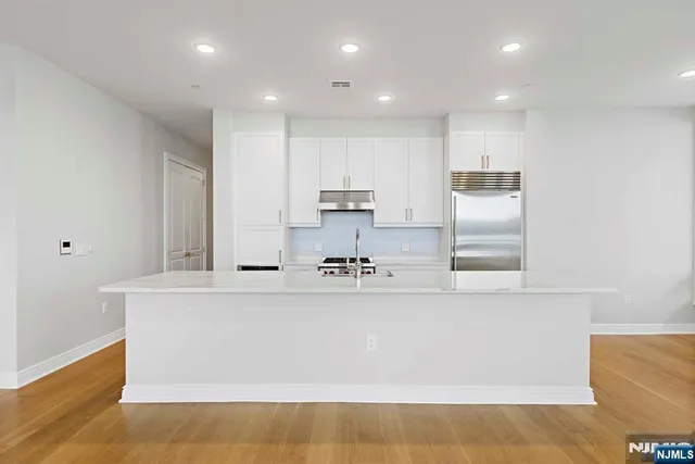 a large kitchen with stainless steel appliances a large counter top a stove and a refrigerator