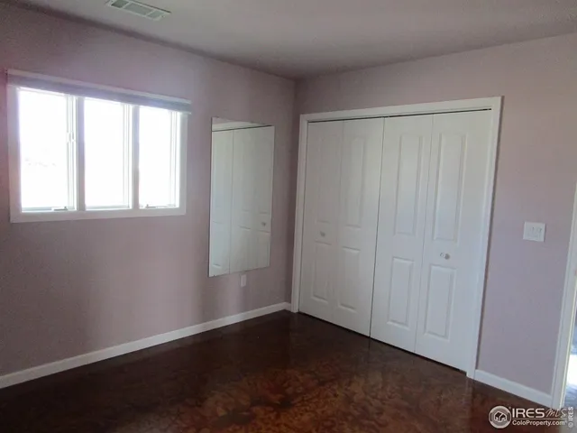 an empty room with wooden floor and windows with curtains