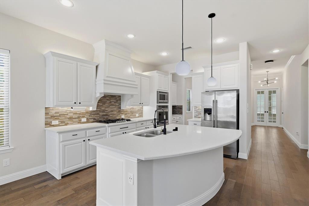 2433 Mare Road Carrollton, TX 75010 - Photo 4 of 37 This open concept kitchen features White shaker cabinetry, built-in stainless steel appliances, recessed lighting, wood flooring, and quartz countertops.
