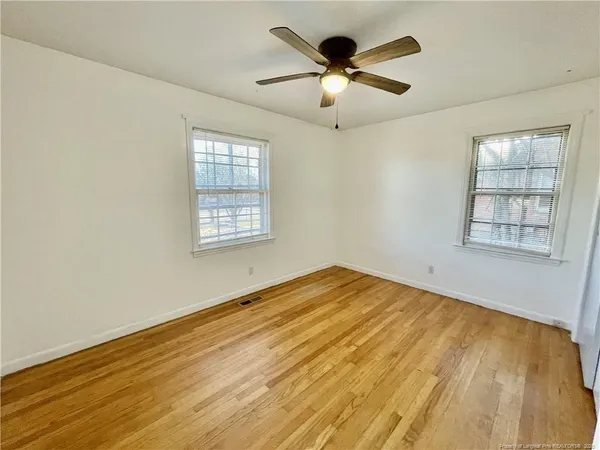an empty room with wooden floor and windows