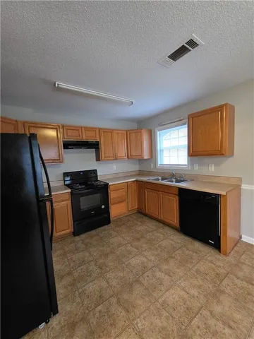 a kitchen with granite countertop a refrigerator and a sink