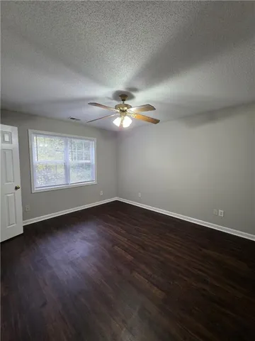 a view of a livingroom with a fan a window and wooden floor