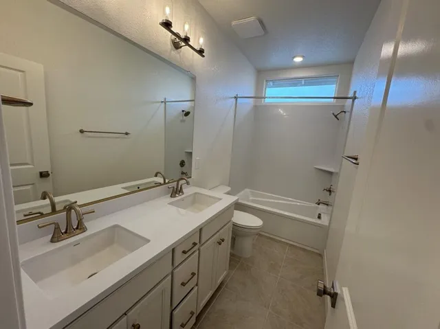 a bathroom with a sink double vanity granite tub shower and a mirror