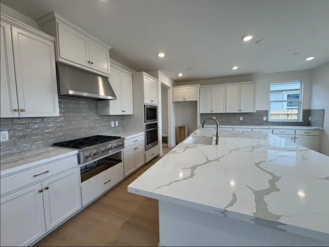 a large kitchen with stainless steel appliances and white cabinets