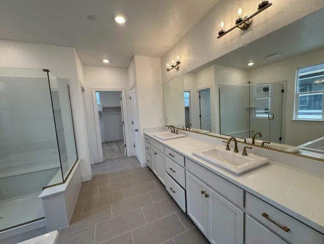 a spacious bathroom with a double vanity sink a large mirror a toilet and a shower