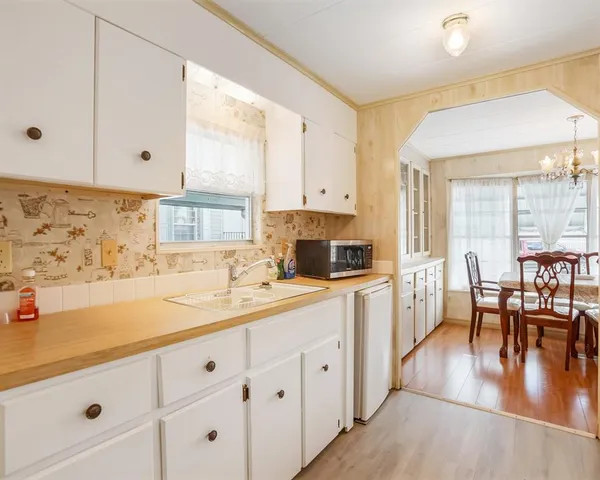 a kitchen with a stove a sink and white cabinets with wooden floor