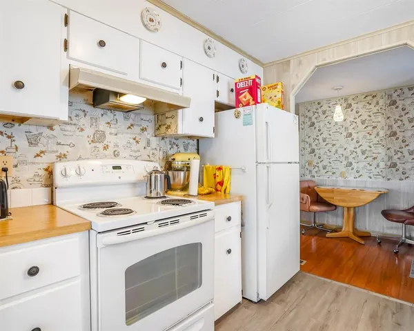 a kitchen with a stove a refrigerator and a wooden floor