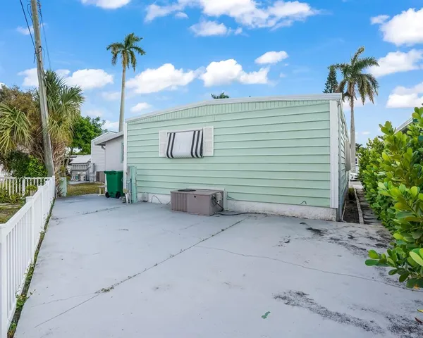 a view of a house with a yard and palm trees