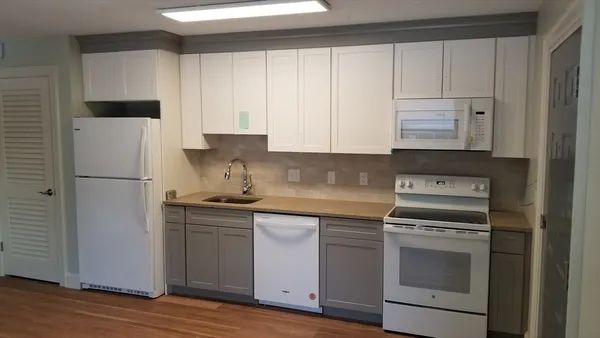 a kitchen with cabinets appliances and wooden floor