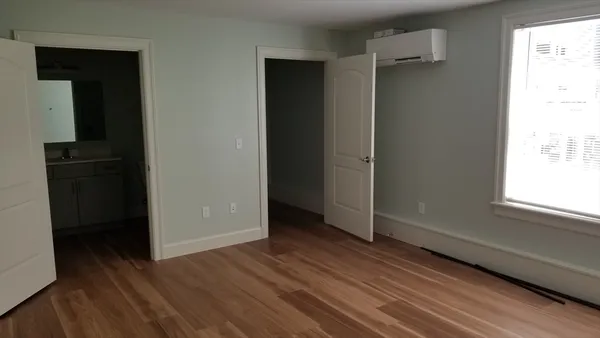 an empty room with wooden floor closet and windows