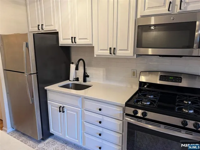 a kitchen with stainless steel appliances a sink a stove and a refrigerator with cabinets