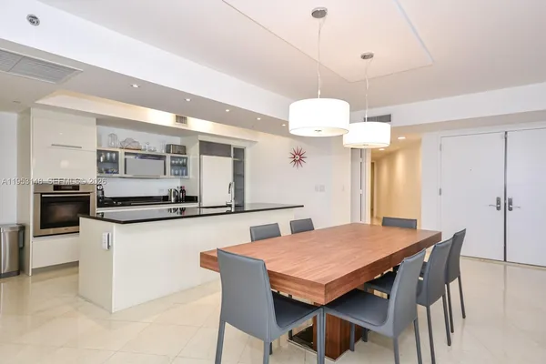 a kitchen with stainless steel appliances granite countertop a kitchen island a table and chairs in it