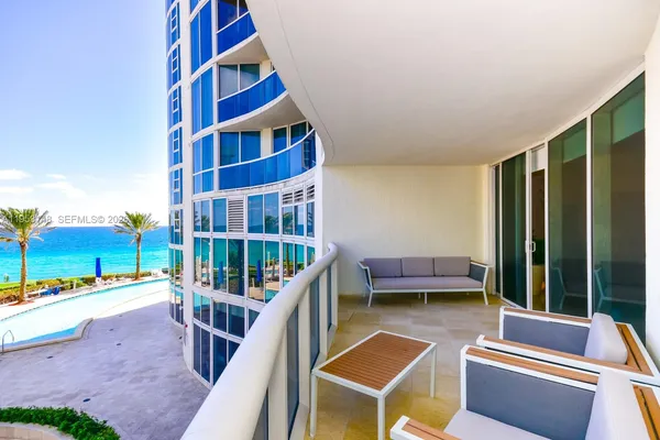 a view of a balcony with chairs and floor to ceiling window and wooden fence