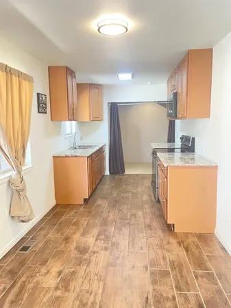a room with kitchen island granite countertop a sink a stove a washer and dryer