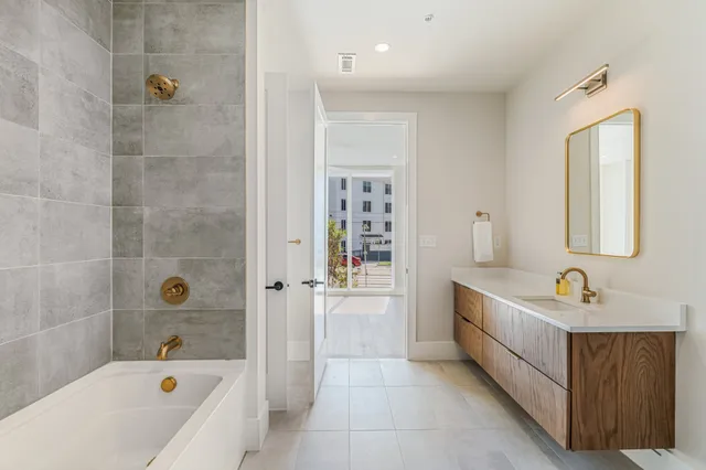 a bathroom with a tub a sink and mirror