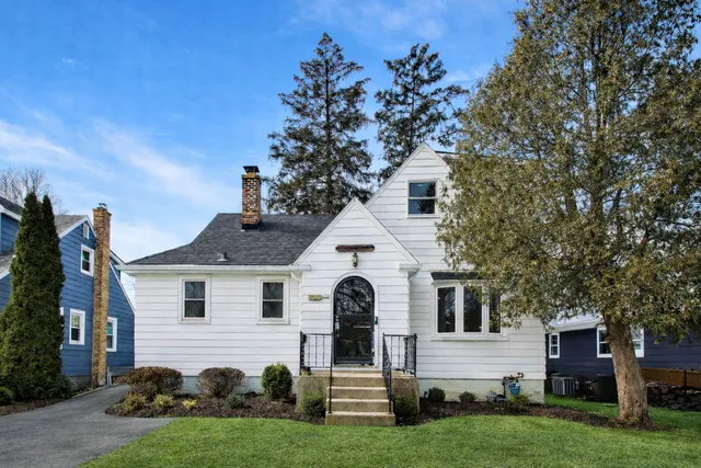 a front view of a house with a garden and trees