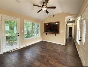 a view of a livingroom with wooden floor a ceiling fan and windows