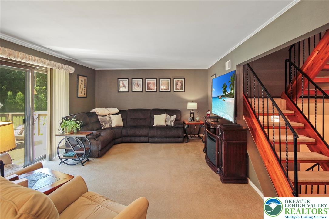 3470 Brodhead Road Bethlehem, PA 18020 - Photo 38 of 84 A comfortable living area with carpeted floors opens to a deck, adjacent to an inviting wooden staircase.