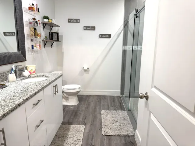 a bathroom with a granite countertop sink a toilet and a mirror