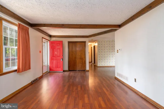a view of an empty room with wooden floor and a window
