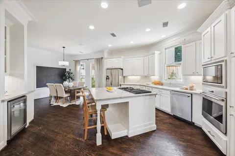 a kitchen with stainless steel appliances kitchen island granite countertop a stove top oven a sink a dining table and chairs