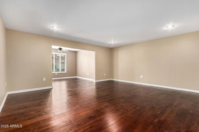 a view of an empty room with wooden floor and windows