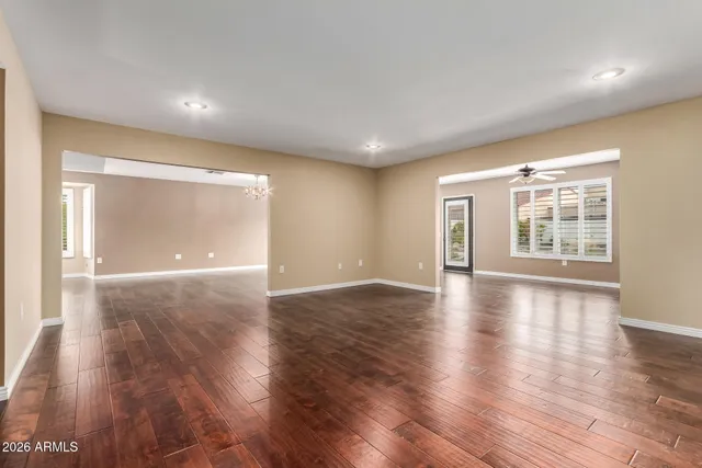 a view of an empty room with wooden floor and windows