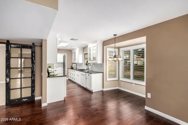 a large white kitchen with wooden floor and a window