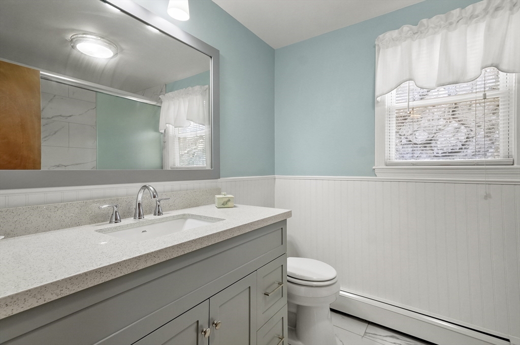 95 Gregory Street Waltham, MA 02451 - Photo 24 of 36 a bathroom with a granite countertop sink a toilet and a mirror