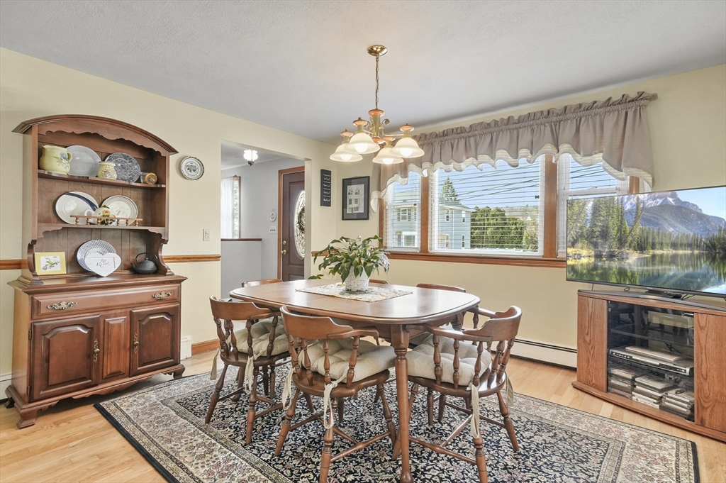 95 Gregory Street Waltham, MA 02451 - Photo 8 of 36 a dining room with wooden floor a chandelier a wooden table and chairs