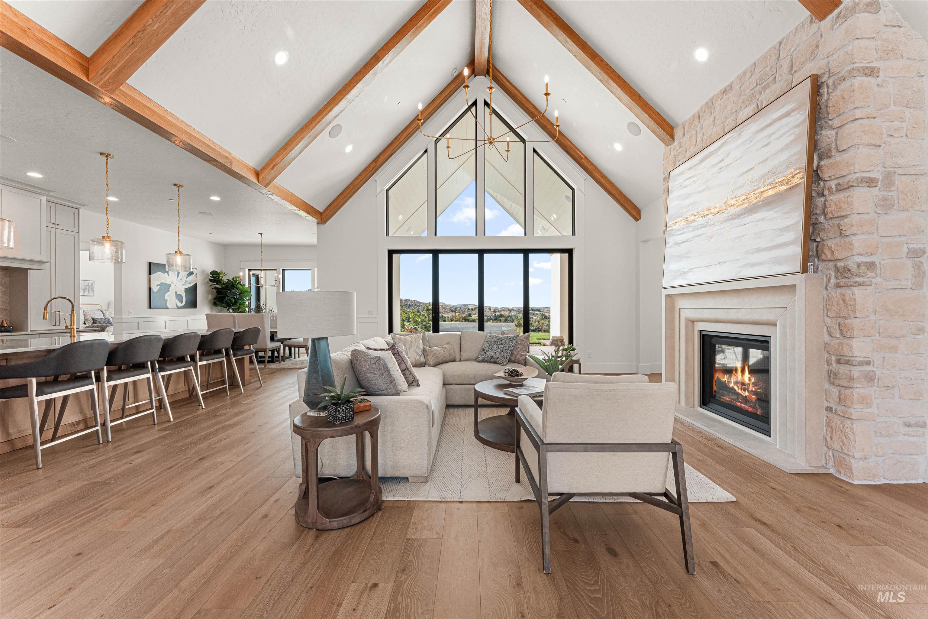 6400 North High Vly Way Eagle, ID 83714 - Photo 11 of 49 Living area with beam ceiling, high vaulted ceiling, light wood-style flooring, a chandelier, and a fireplace