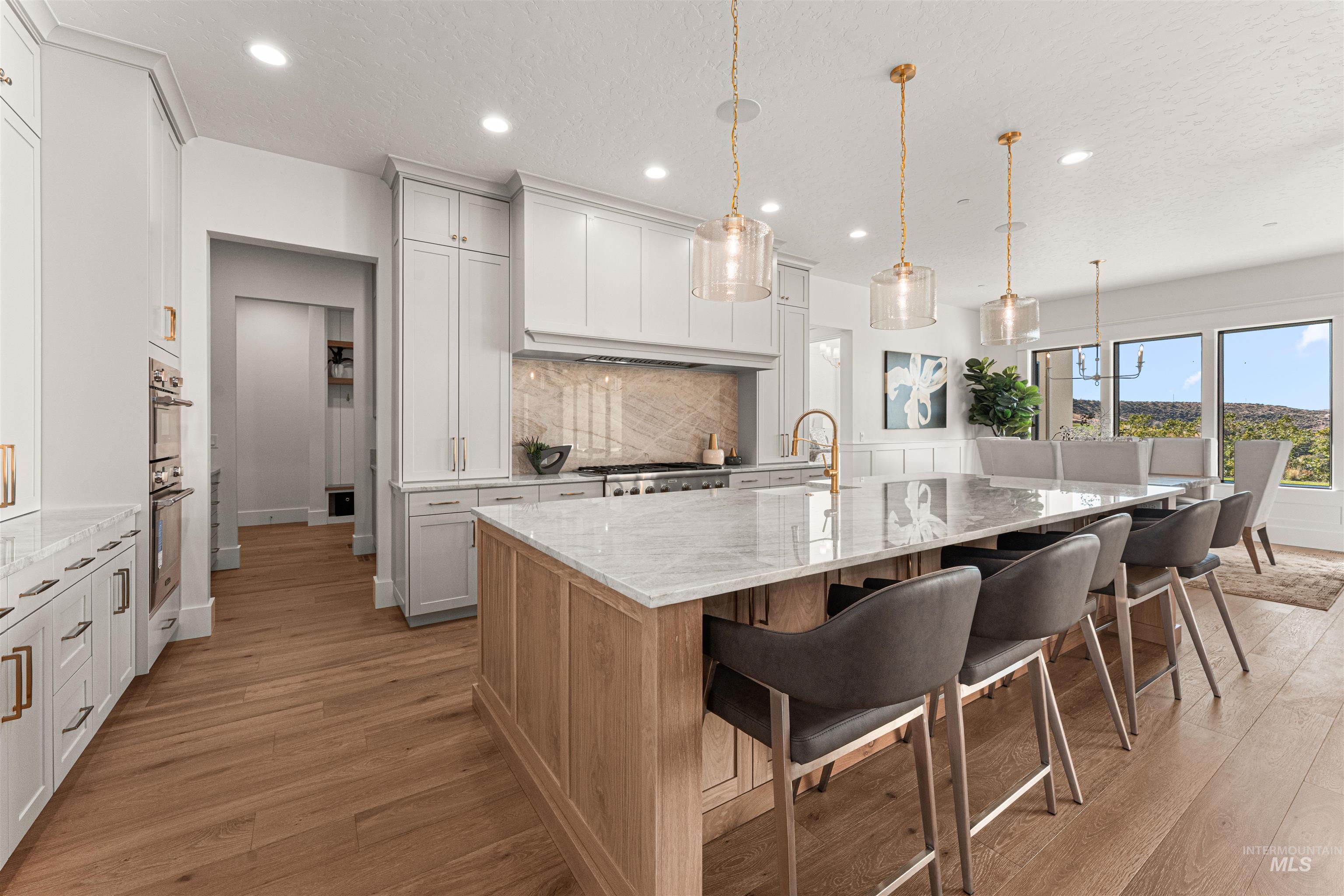 6400 North High Vly Way Eagle, ID 83714 - Photo 6 of 49 Kitchen featuring light stone countertops, a spacious island, a breakfast bar area, decorative light fixtures, and light wood-style floors