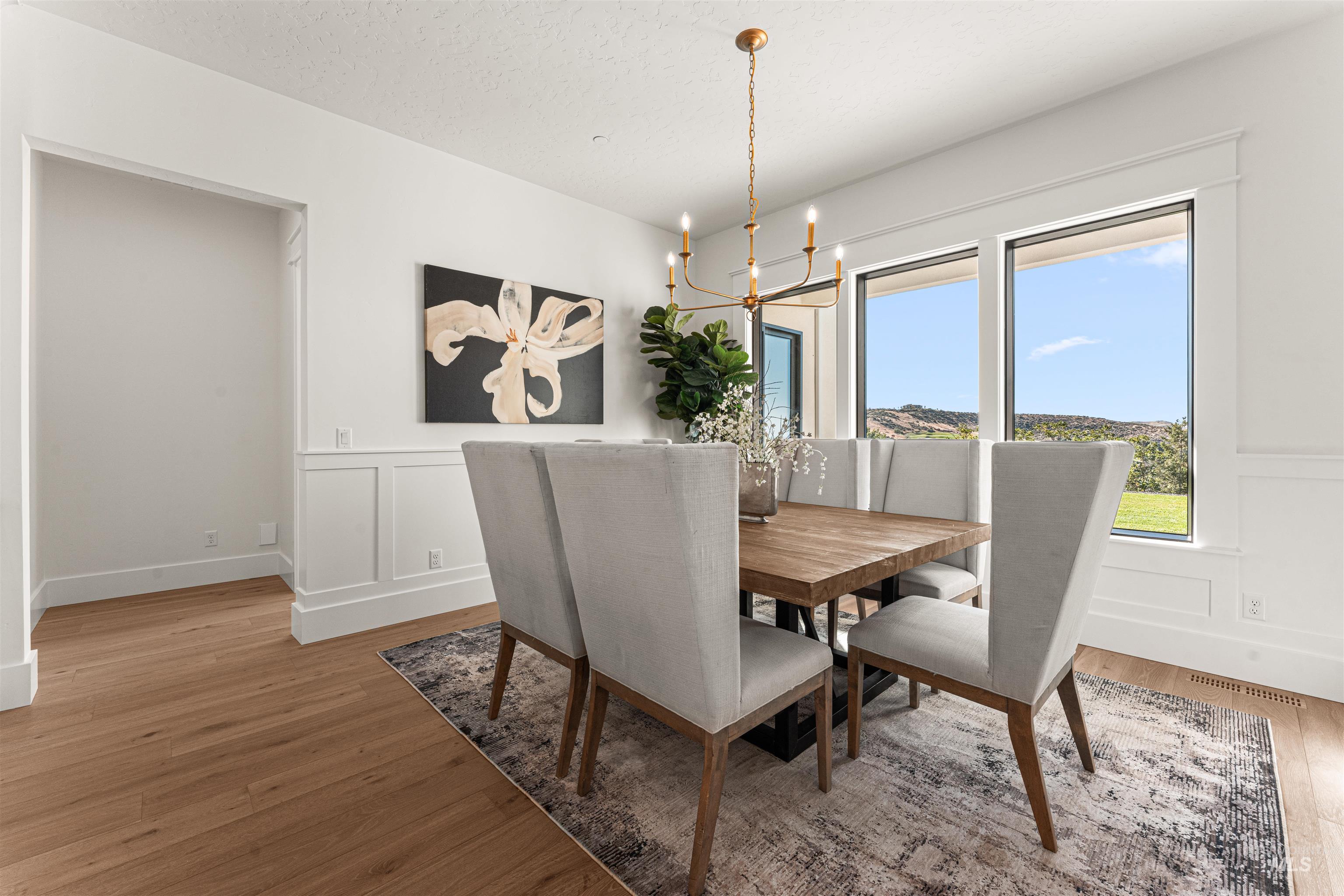 6400 North High Vly Way Eagle, ID 83714 - Photo 9 of 49 Dining room featuring a decorative wall, a wainscoted wall, a chandelier, light wood-style floors, and a textured ceiling