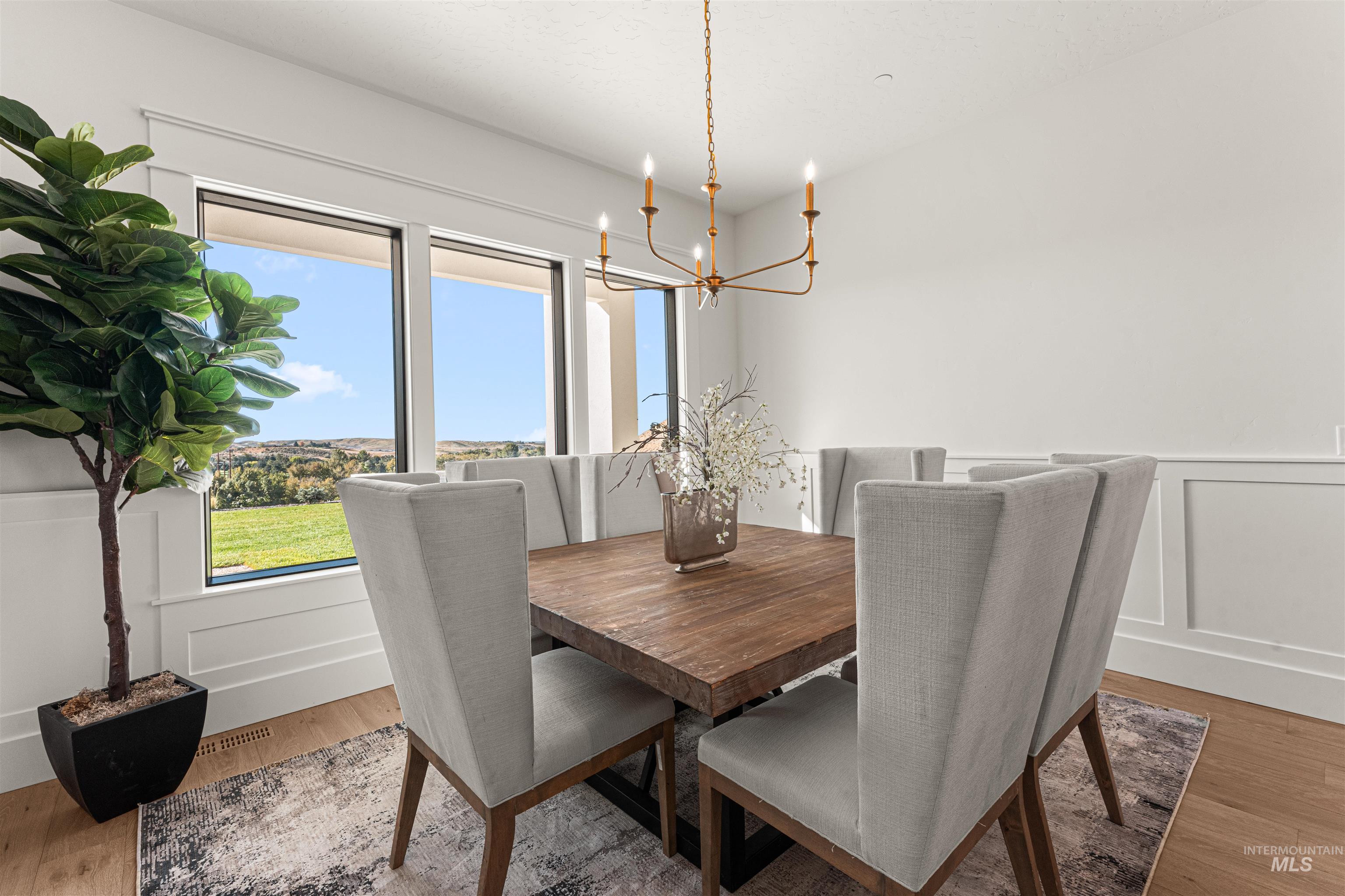 6400 North High Vly Way Eagle, ID 83714 - Photo 10 of 49 Dining space featuring a decorative wall, light wood-style floors, a wainscoted wall, and a chandelier