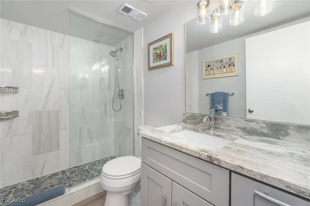 a bathroom with a granite countertop sink toilet and shower
